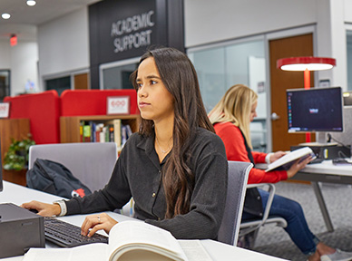 student working at a computer in the library
